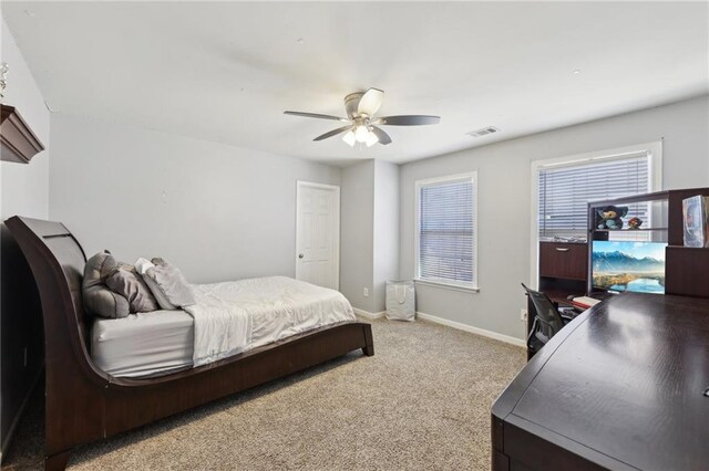 bedroom featuring baseboards, multiple windows, visible vents, and light colored carpet