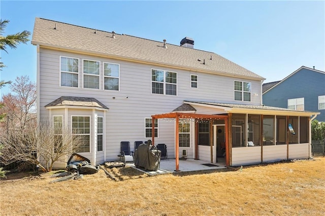 rear view of house with a sunroom, a patio area, a chimney, and a yard