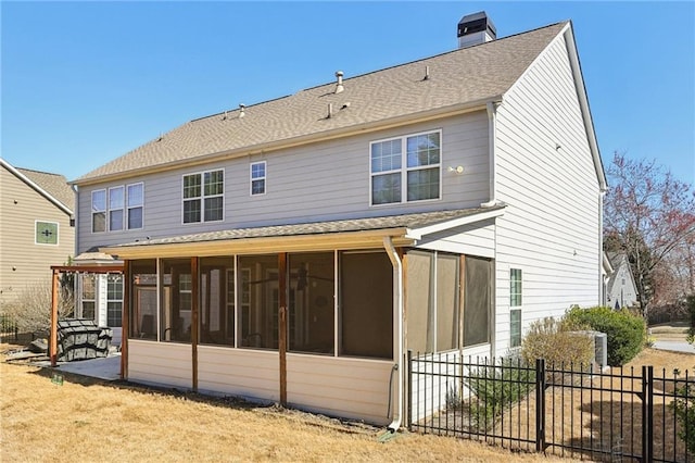 back of house with a chimney, a shingled roof, a sunroom, a patio area, and fence