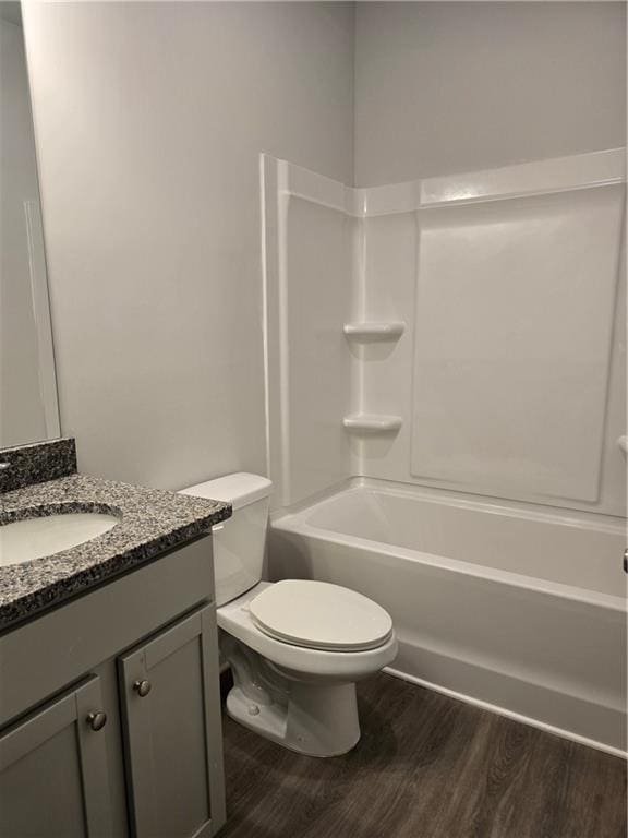 full bathroom featuring washtub / shower combination, hardwood / wood-style flooring, vanity, and toilet