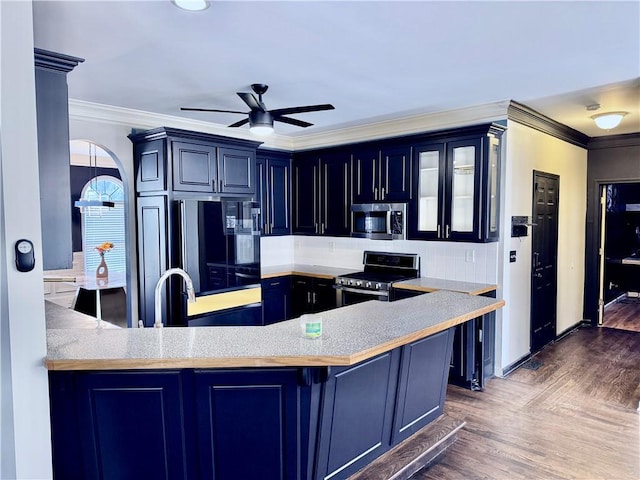 kitchen featuring ceiling fan, dark hardwood / wood-style flooring, kitchen peninsula, appliances with stainless steel finishes, and ornamental molding