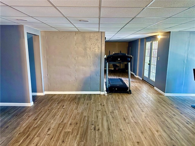 workout room featuring a paneled ceiling, french doors, and wood-type flooring