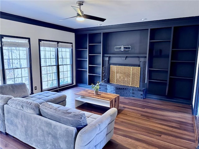 living room with dark hardwood / wood-style flooring, crown molding, built in features, and ceiling fan