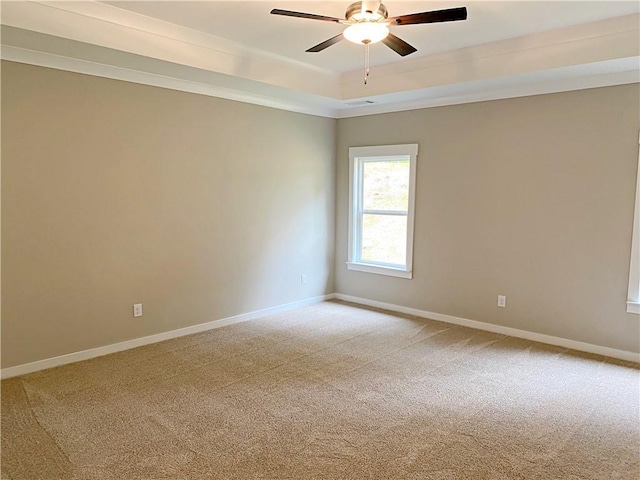 spare room featuring ceiling fan, light colored carpet, baseboards, and a raised ceiling