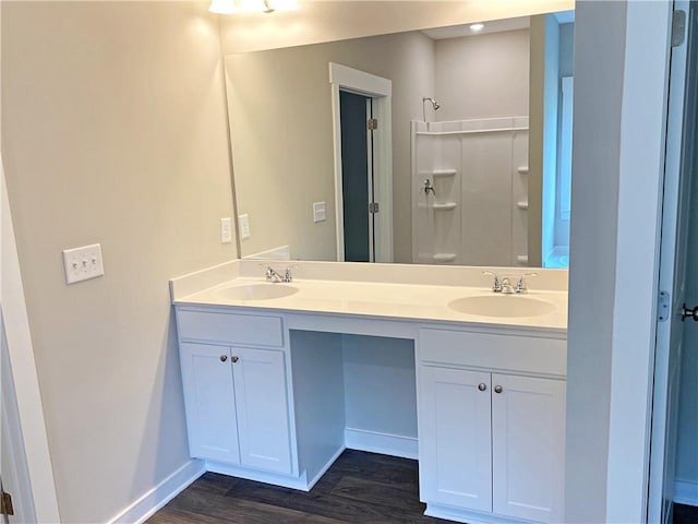 full bath featuring a sink, double vanity, a shower, and wood finished floors