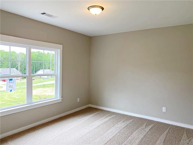 unfurnished room with baseboards, light colored carpet, and visible vents