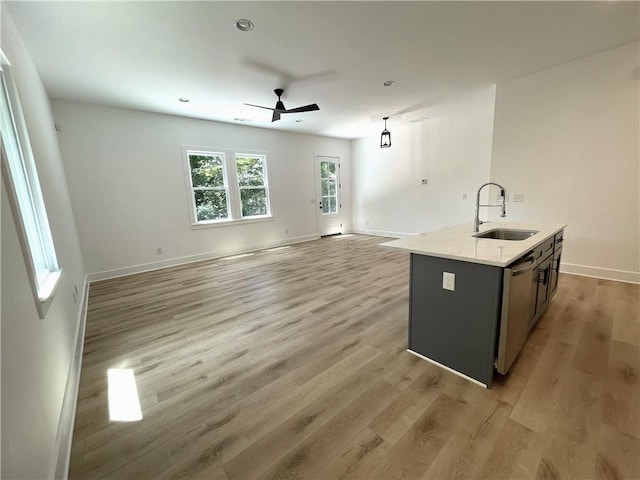 kitchen featuring ceiling fan, an island with sink, light wood-type flooring, dishwasher, and sink