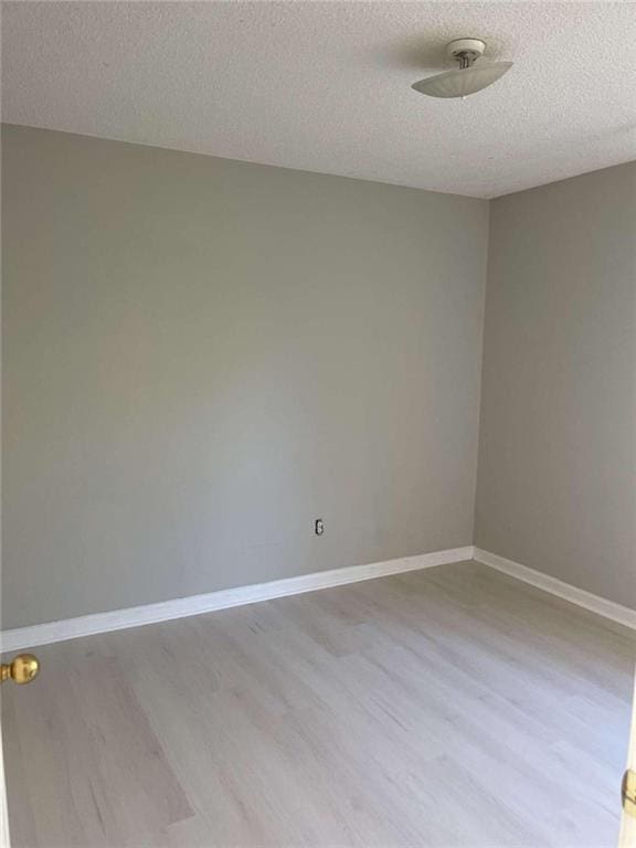 unfurnished room featuring light hardwood / wood-style floors and a textured ceiling