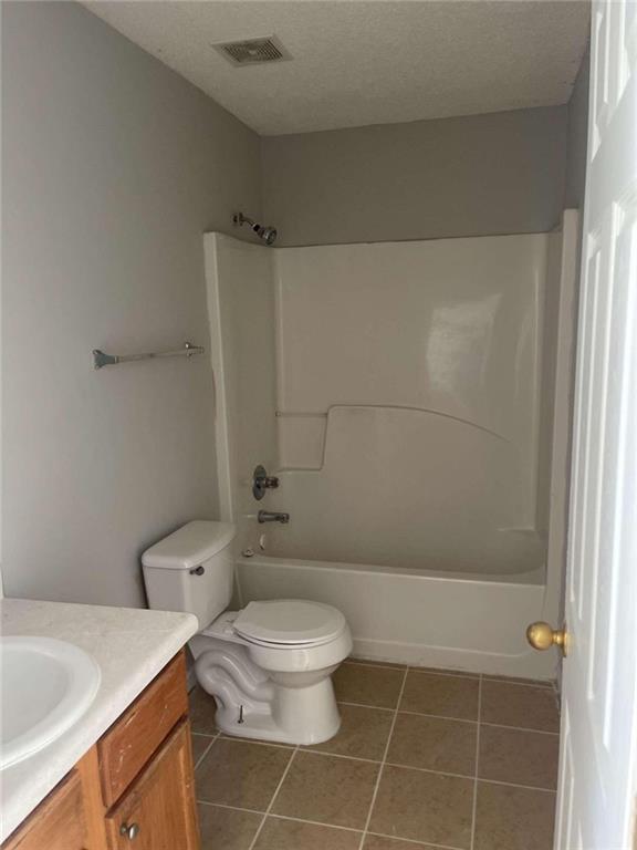 full bathroom with vanity, tile patterned floors, a textured ceiling, and toilet