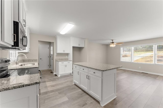1292 Fernside Dr, Toccoa, GA 30577 - kitchen with stainless steel microwave, light wood-type flooring, a sink, a ceiling fan, and white cabinets
