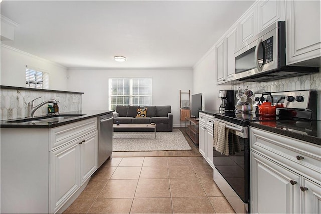 kitchen featuring a sink, appliances with stainless steel finishes, ornamental molding, and dark countertops