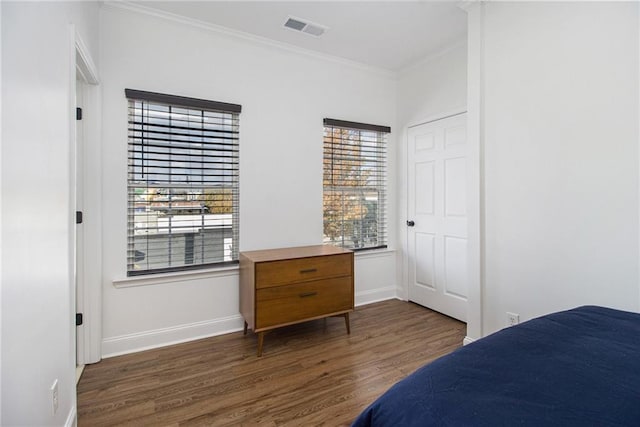 bedroom featuring baseboards, visible vents, ornamental molding, and wood finished floors
