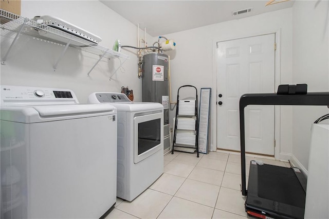 laundry area with laundry area, visible vents, washing machine and dryer, light tile patterned floors, and electric water heater