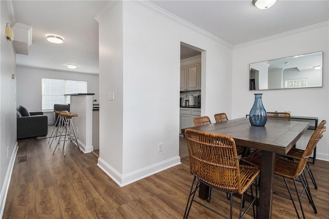 dining area with baseboards, ornamental molding, and wood finished floors