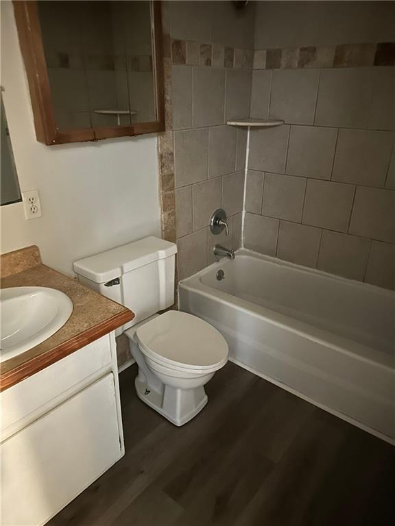 full bathroom featuring tiled shower / bath, toilet, vanity, and hardwood / wood-style flooring