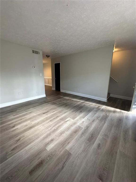 unfurnished room featuring a textured ceiling and dark wood-type flooring