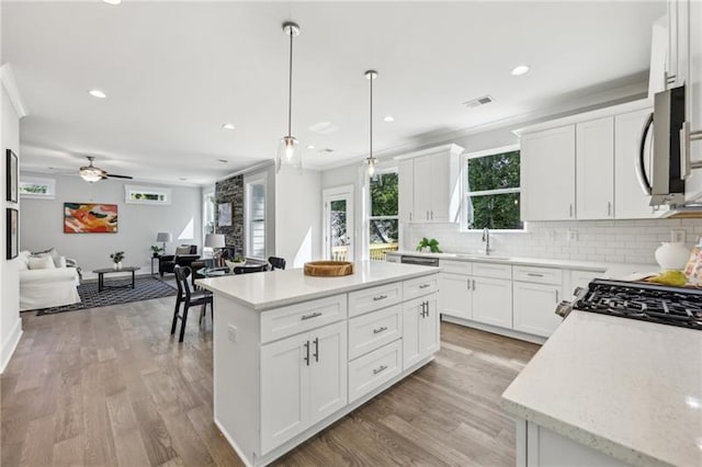 kitchen featuring white cabinetry, ceiling fan, a center island, and decorative light fixtures