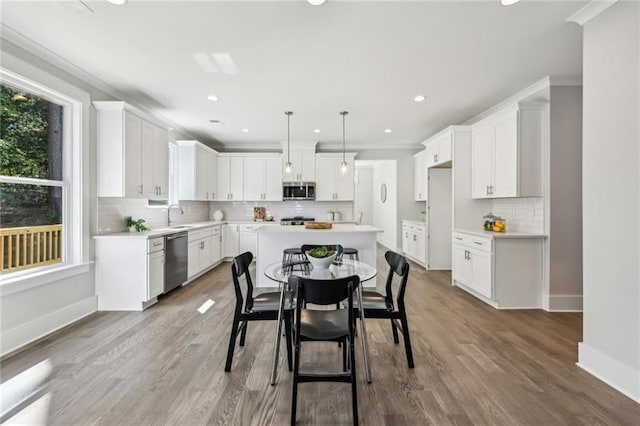 kitchen featuring pendant lighting, white cabinetry, hardwood / wood-style flooring, appliances with stainless steel finishes, and a center island