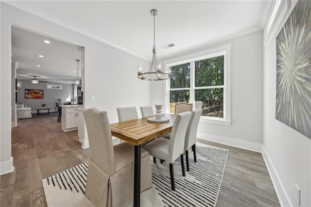 dining area featuring ceiling fan with notable chandelier, ornamental molding, and dark hardwood / wood-style flooring