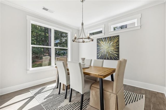 dining space with an inviting chandelier, crown molding, and dark hardwood / wood-style floors