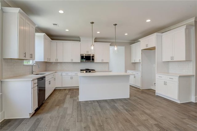 kitchen featuring white cabinets, pendant lighting, appliances with stainless steel finishes, a center island, and light hardwood / wood-style floors