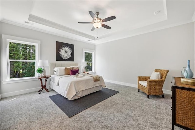 carpeted bedroom featuring ceiling fan, a tray ceiling, and multiple windows