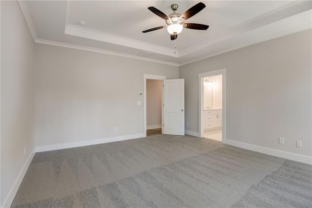 unfurnished bedroom with ceiling fan, ornamental molding, a tray ceiling, carpet floors, and ensuite bathroom