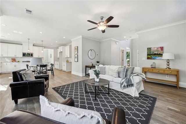 living room featuring light hardwood / wood-style floors, ornamental molding, and ceiling fan