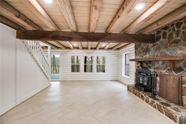 unfurnished living room with light parquet floors, a wood stove, and beam ceiling