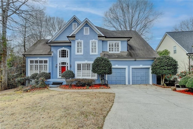 traditional-style home featuring concrete driveway, a front lawn, an attached garage, and stucco siding