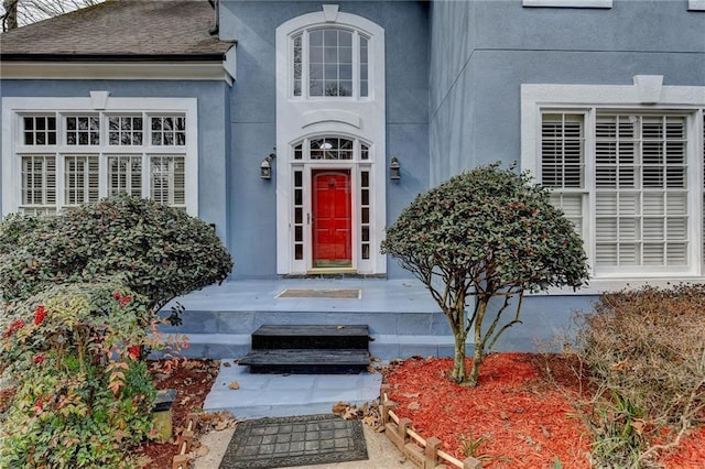 doorway to property with roof with shingles and stucco siding