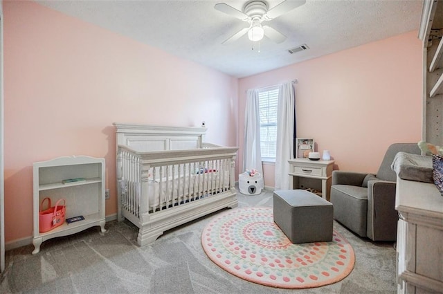 bedroom with ceiling fan, light carpet, and a crib