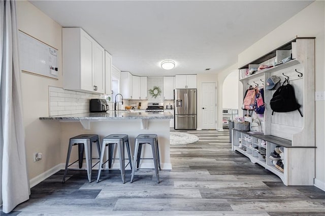 kitchen featuring white cabinets, decorative backsplash, kitchen peninsula, and appliances with stainless steel finishes