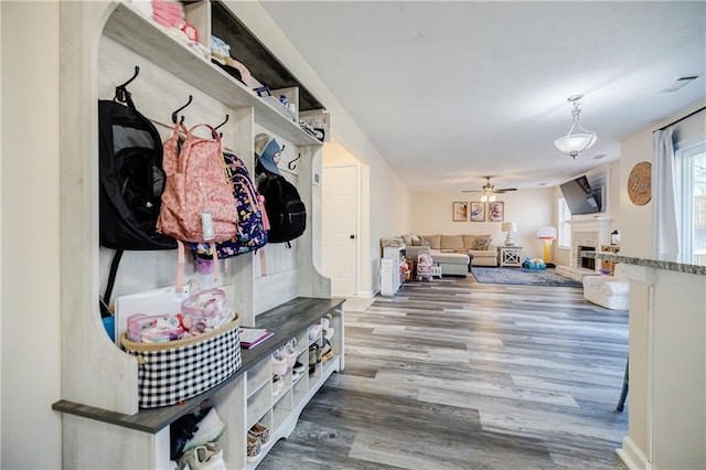 mudroom featuring hardwood / wood-style floors, a brick fireplace, and ceiling fan