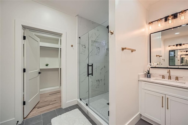 bathroom featuring tile patterned floors, a marble finish shower, vanity, and baseboards