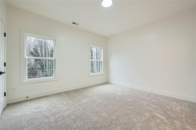 carpeted empty room featuring baseboards and visible vents