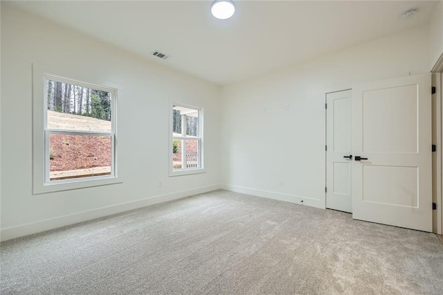 unfurnished room with baseboards, visible vents, and light colored carpet