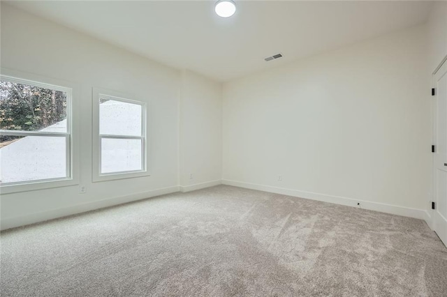 unfurnished room with visible vents, light carpet, and baseboards