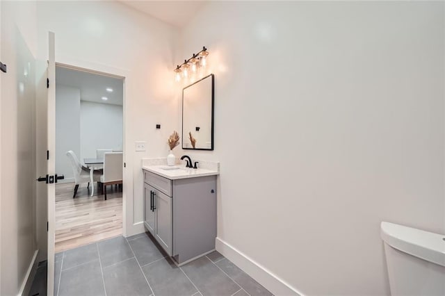 bathroom with toilet, tile patterned flooring, baseboards, and vanity