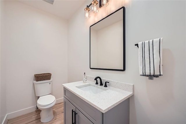 bathroom featuring toilet, baseboards, wood finished floors, and vanity