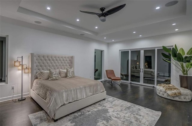 bedroom featuring access to exterior, ceiling fan, french doors, dark hardwood / wood-style floors, and a tray ceiling