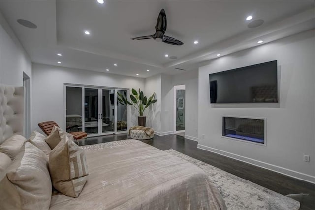 bedroom featuring dark hardwood / wood-style flooring, a tray ceiling, and ceiling fan