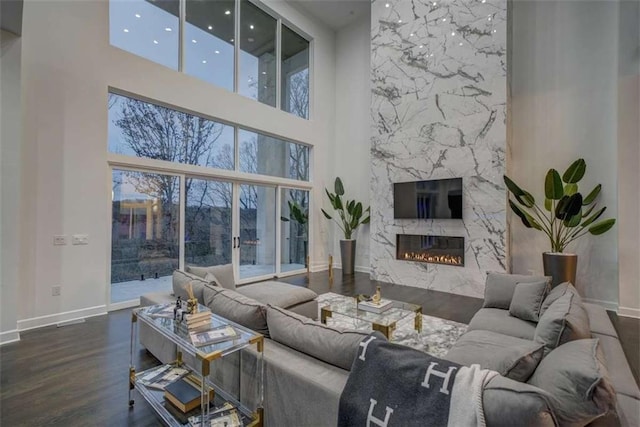 living room with a fireplace, dark hardwood / wood-style flooring, a towering ceiling, and plenty of natural light