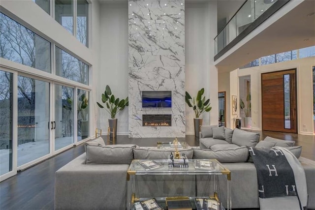 living room with hardwood / wood-style floors, a healthy amount of sunlight, a towering ceiling, and a fireplace