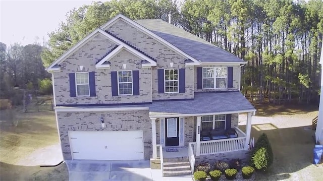 view of front of house featuring a porch, brick siding, driveway, and a garage