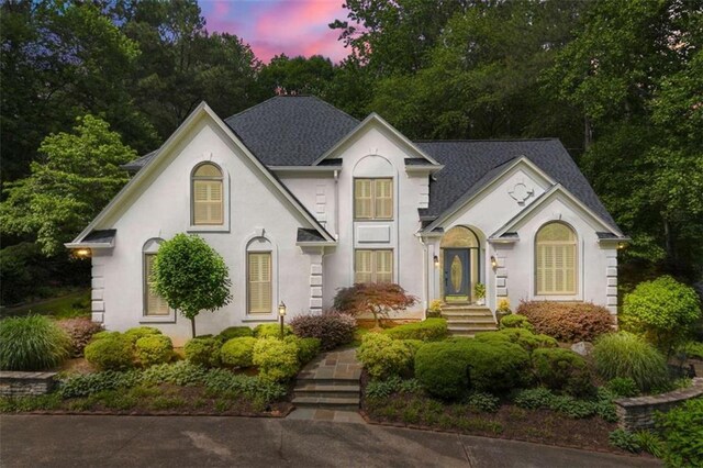 312 Crabapple Springs Way, Woodstock, GA 30188 - french country style house with stucco siding, view of wooded area, and roof with shingles