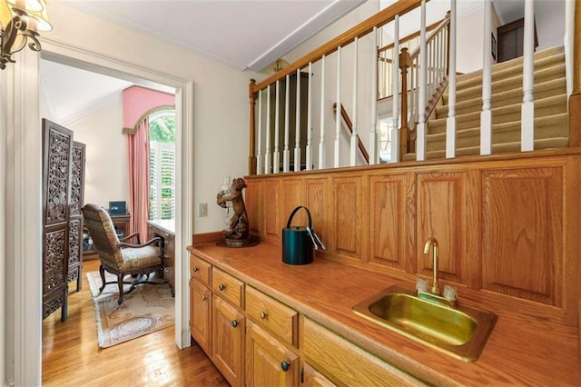 312 Crabapple Springs Way, Woodstock, GA 30188 - kitchen with a sink, ornamental molding, light countertops, light wood finished floors, and brown cabinets