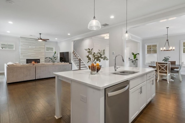 kitchen with a sink, a fireplace, stainless steel dishwasher, ceiling fan with notable chandelier, and visible vents