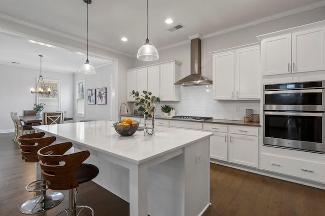 kitchen with white cabinets, visible vents, wall chimney exhaust hood, and appliances with stainless steel finishes