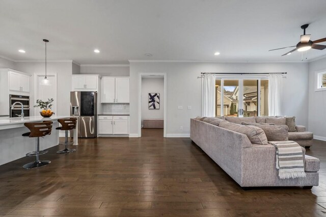 living room featuring a fireplace, ornamental molding, dark hardwood / wood-style floors, and ceiling fan